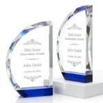 Two clear curved crystal award designs with blue bases